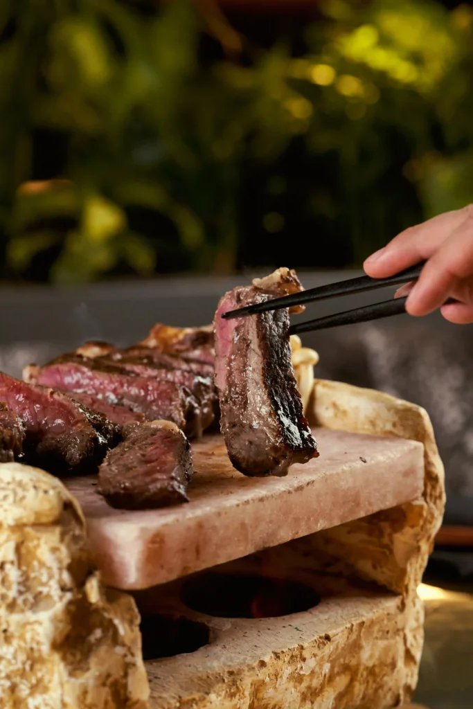 Image of a person picking up steak at Amelia Restaurant & Lounge